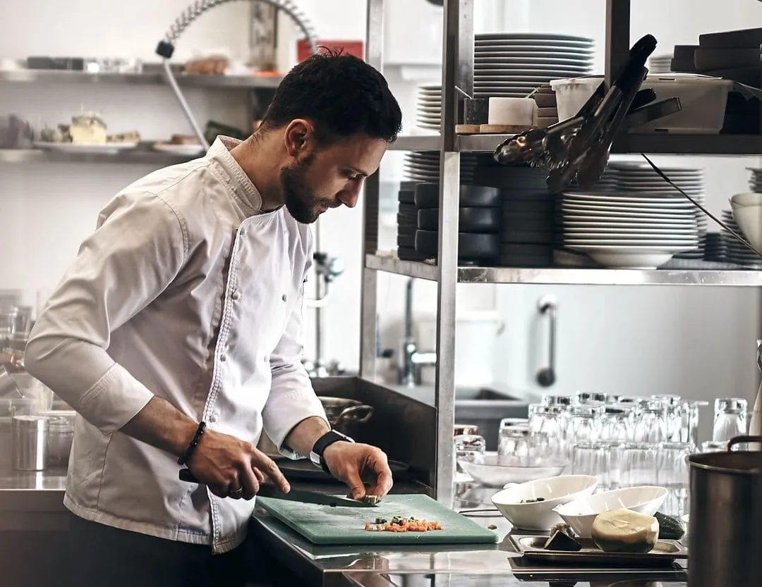 A chef prepares a dish on the counter of a professional kitchen